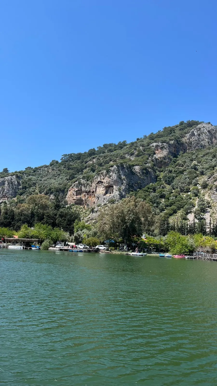 The Kaunos rock tombs cut into the cliff above the Dalyan river, seen from the water on a clear summer day